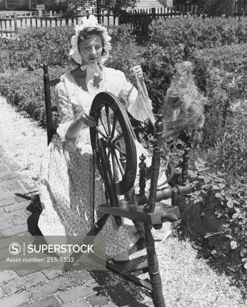 USA, Massachusetts, Ipswich, Young women spinning flax in garden of John Whipple House