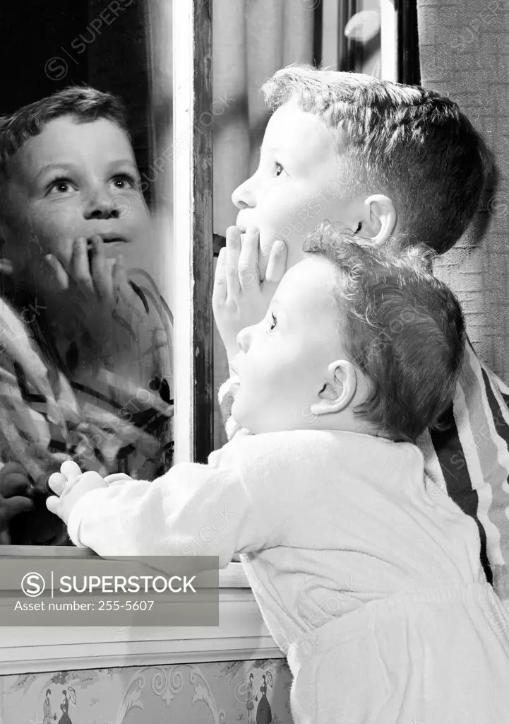 Two kids looking through window