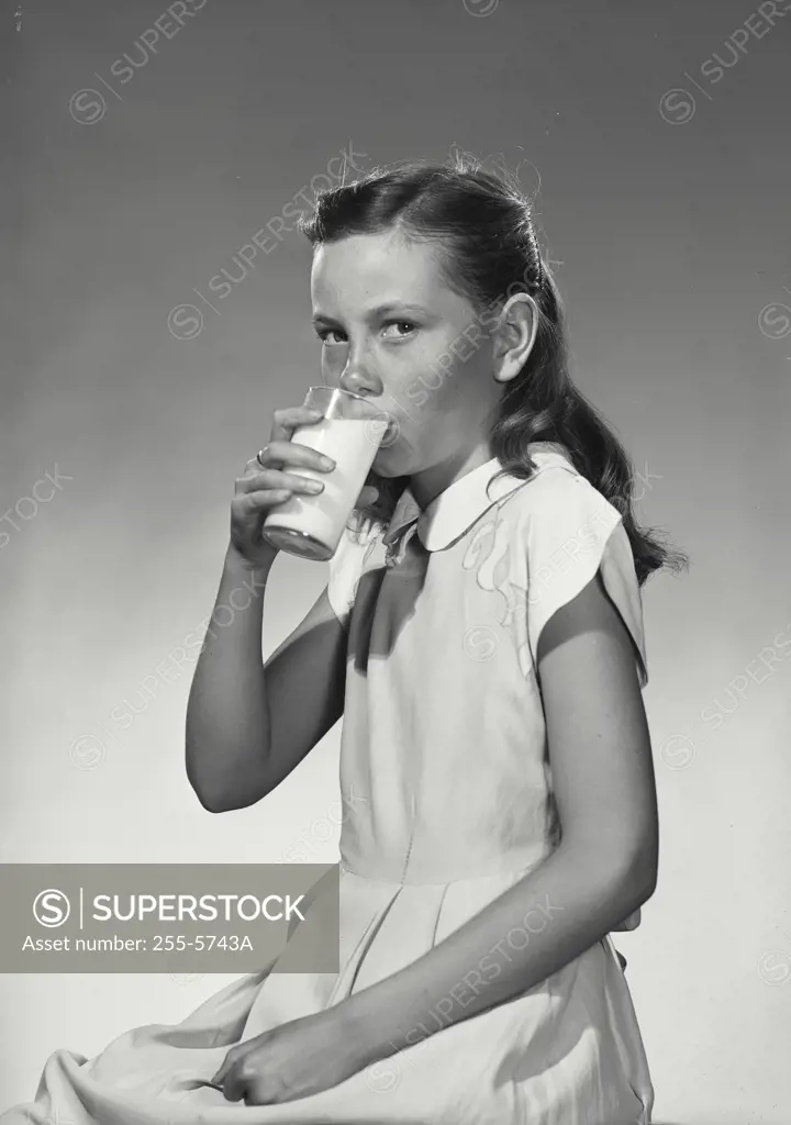 Vintage Photograph. Girl in white dress drinking glass of milk