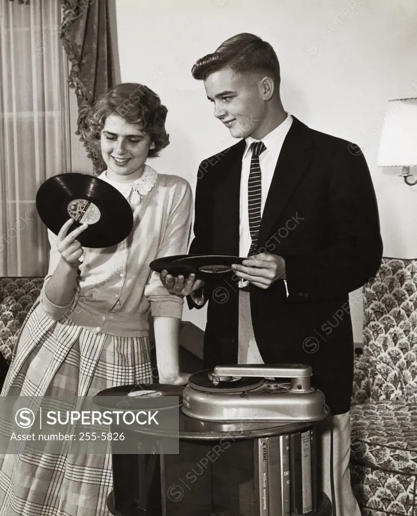 Young couple holding records near turntable