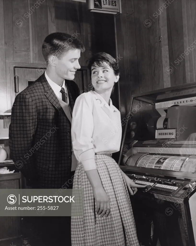 Side profile of a teenage couple standing near a jukebox
