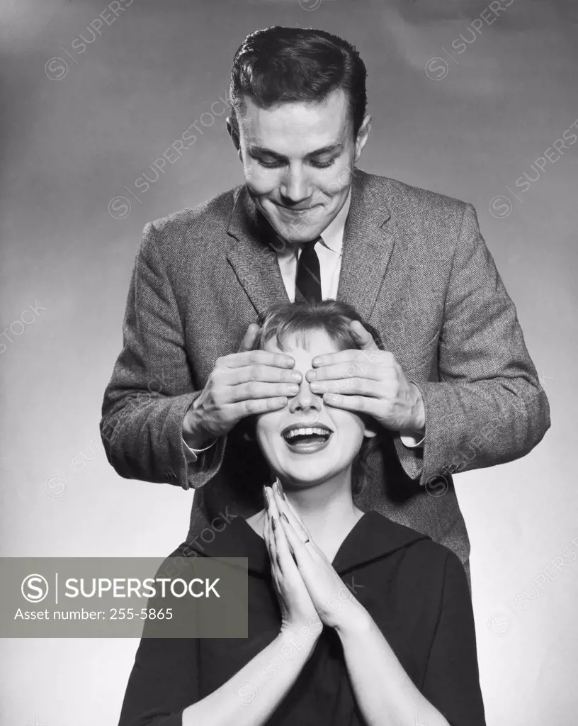 Young man covering the eyes of a young woman from behind