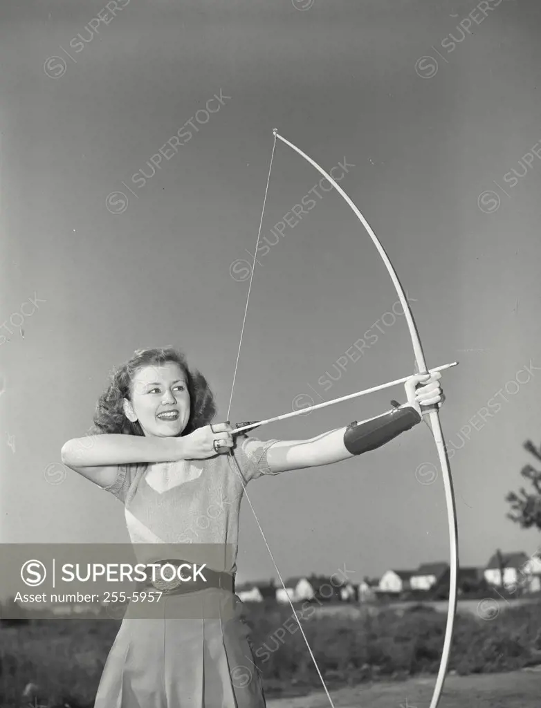 Vintage photograph. Young woman aiming bow and arrow