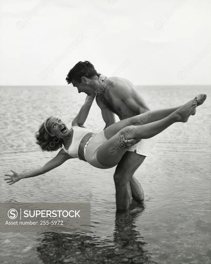 Young man carrying young woman on beach