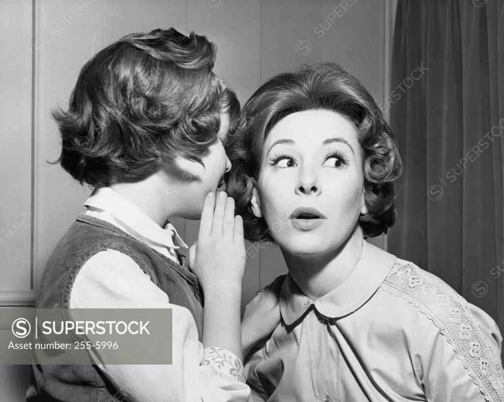 Side profile of a daughter whispering into her mother's ear