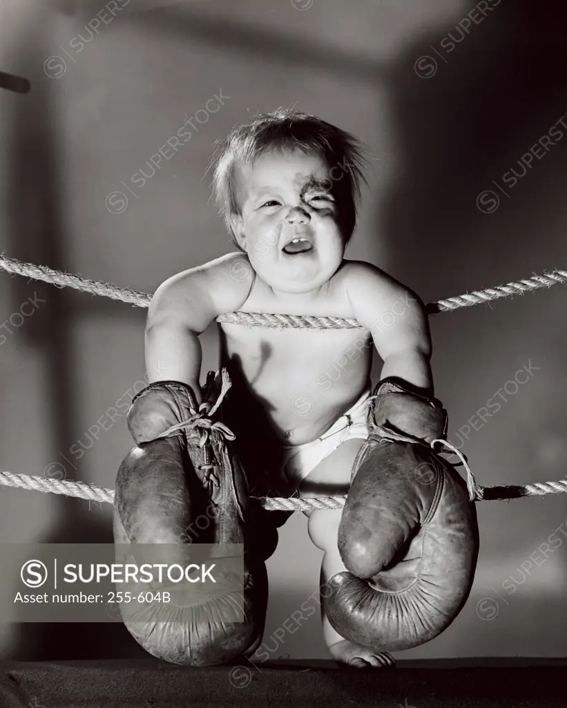 Crying baby wearing boxing gloves