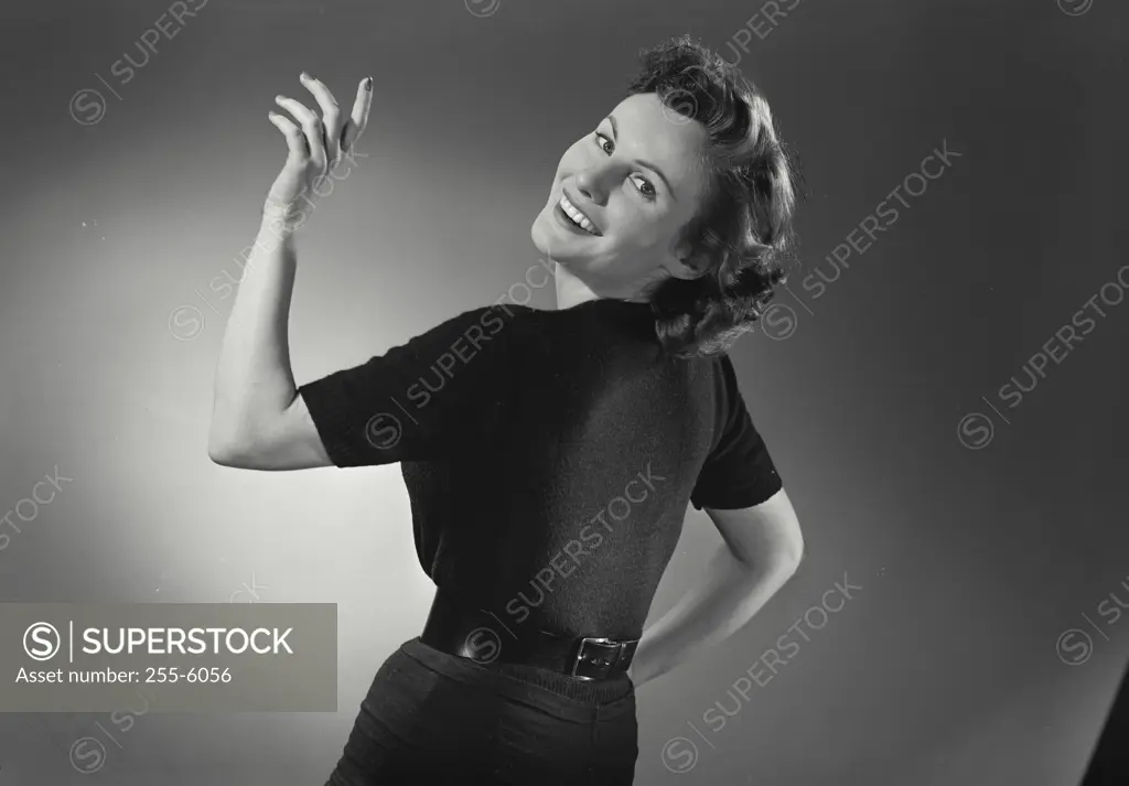 Vintage Photograph. Woman in black dress smiling over shoulder with hand up