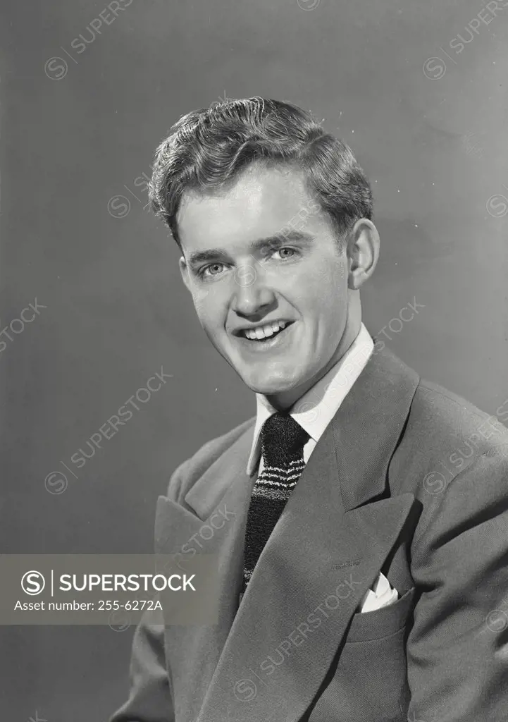 Portrait of Young man with wavy hair wearing suit and tie smiling