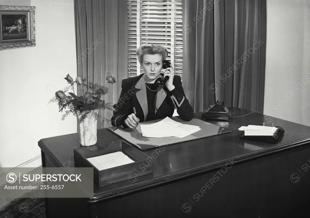 Vintage Photograph. Woman at desk talking on telephone with concerned expression