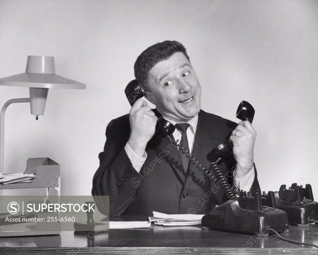 Businessman using two telephones