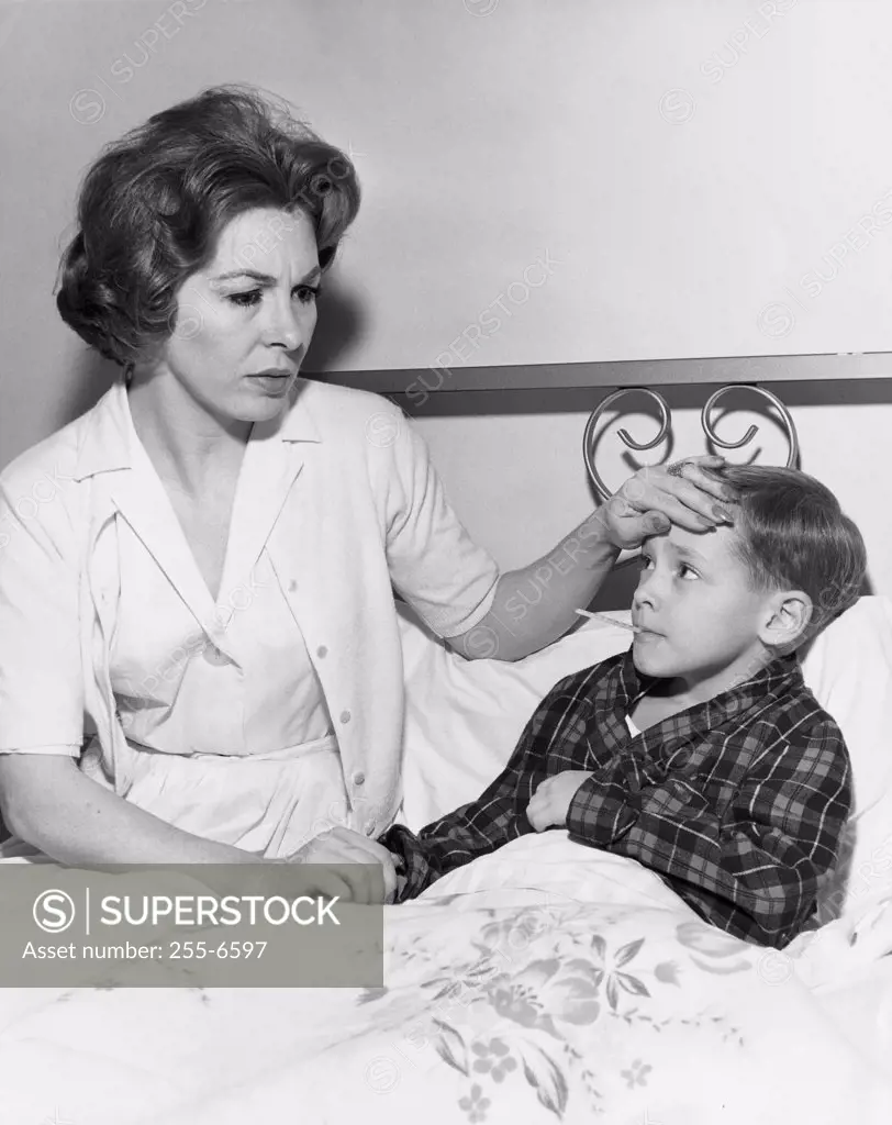 Female pediatrician checking temperature of a boy