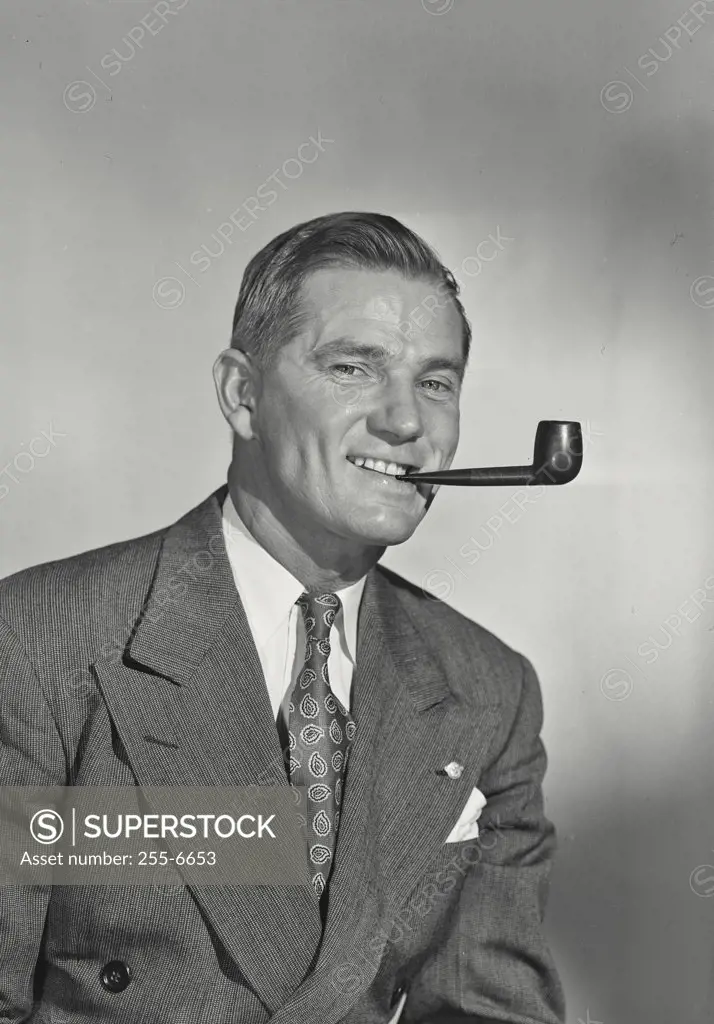 Studio portrait of smiling man with pipe
