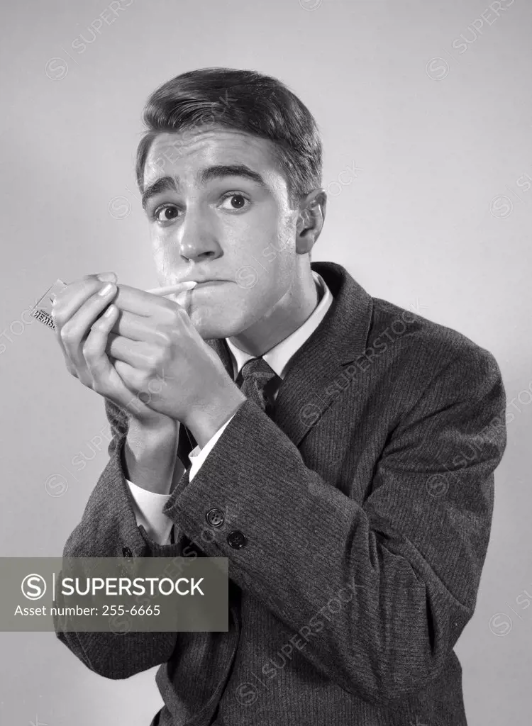 Studio portrait of young man igniting cigarette