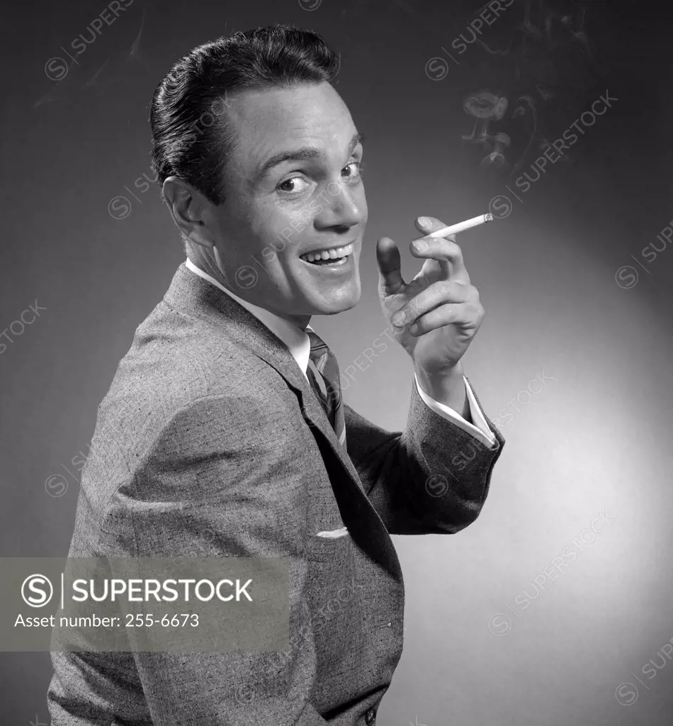 Studio portrait of smiling man holding cigarette