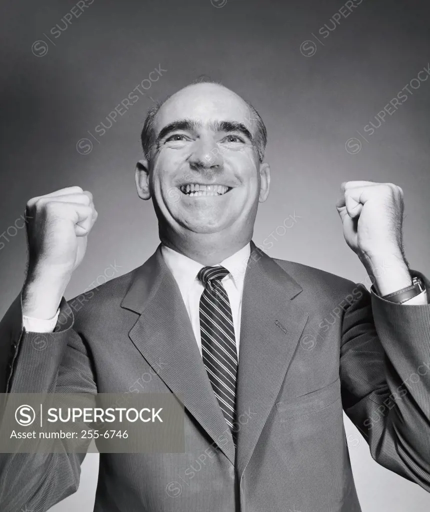 Close-up of a businessman smiling with his fists clenched