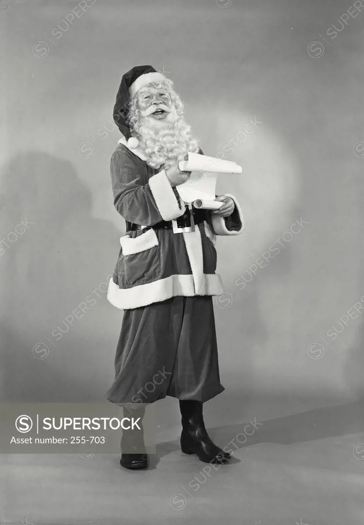 Vintage photograph. Man in Santa Claus costume smiling holding list of names