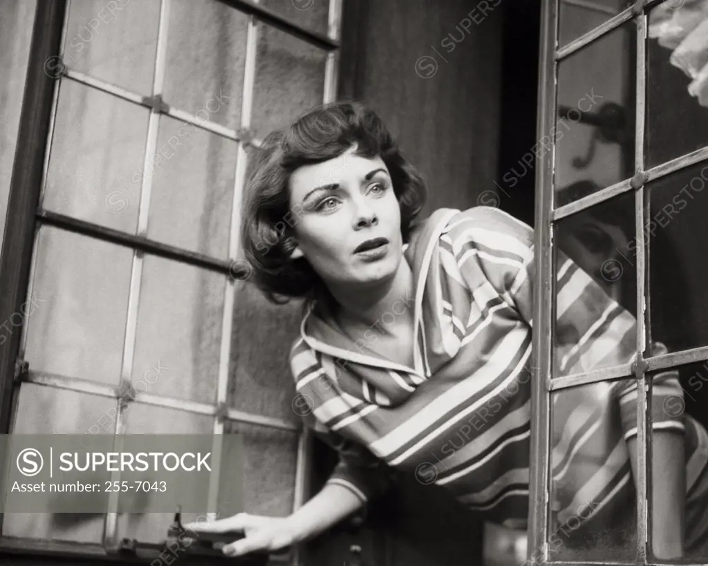 Close-up of a young woman peeking through a window