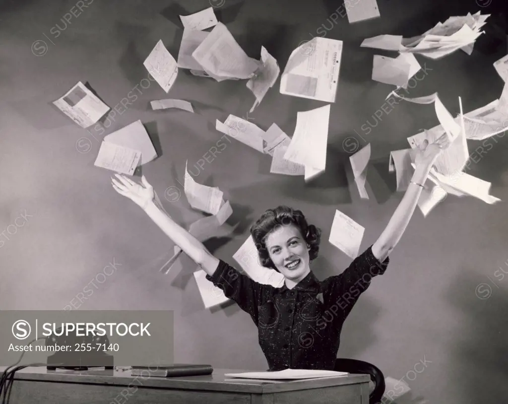 Businesswoman throwing papers in office