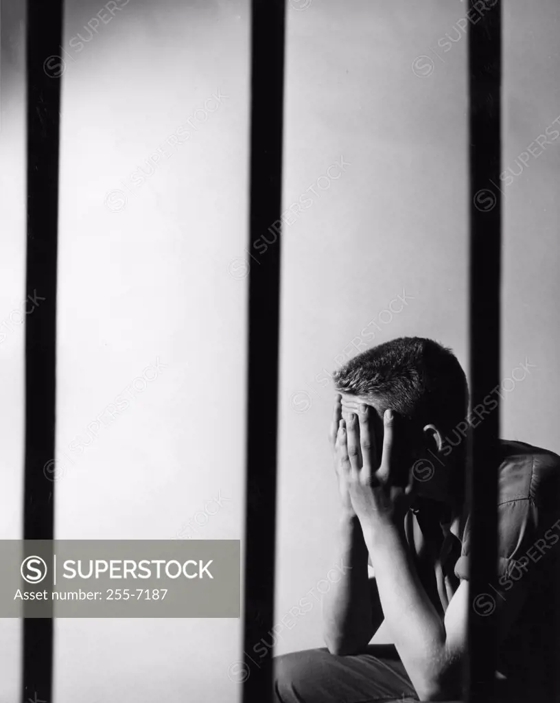 Male prisoner sitting in prison cell