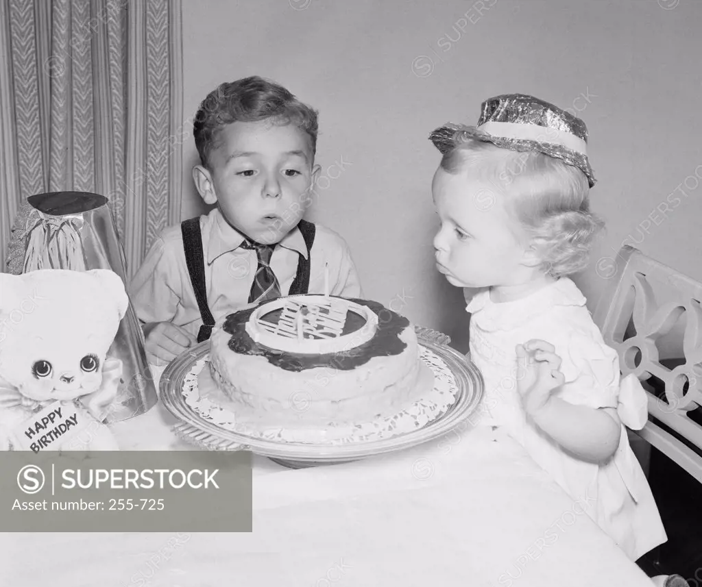 Children blowing candles on birthday cake