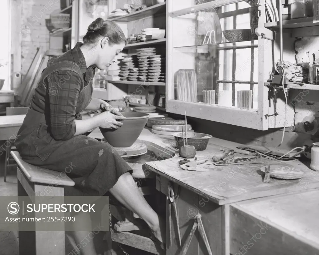 Young woman making pottery on a pottery wheel