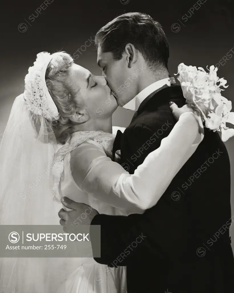 Side profile of a newlywed couple kissing