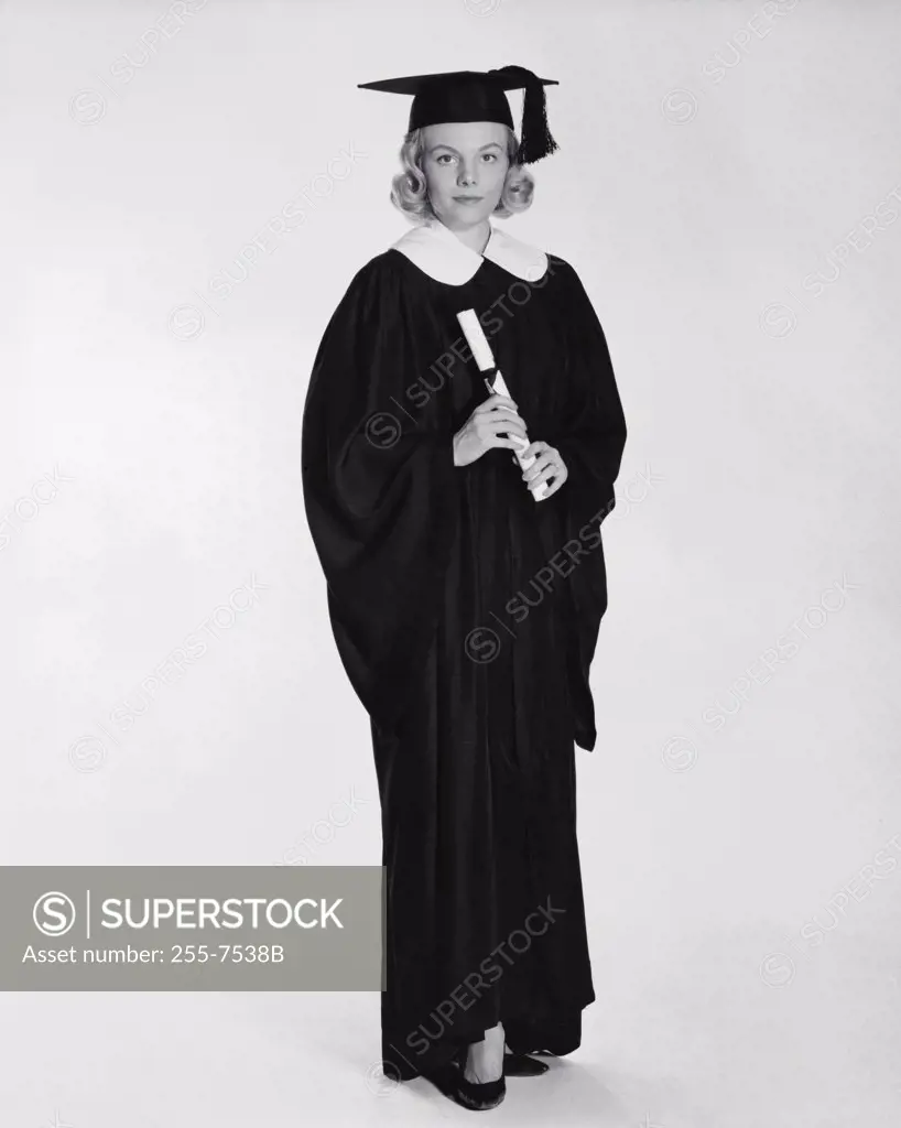 Young woman wearing a graduation gown and holding a diploma