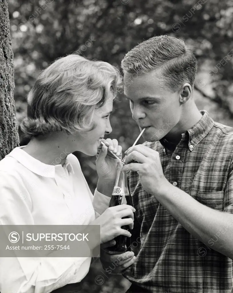 Close-up of a teenage couple sharing a bottle of soda