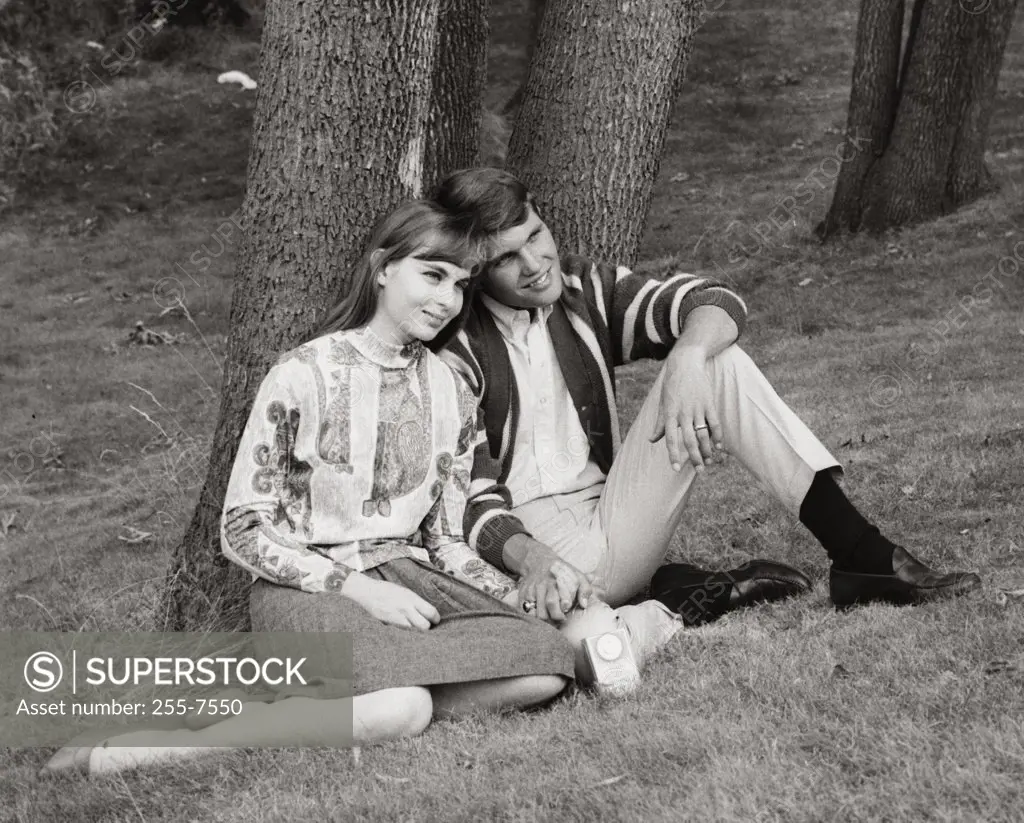 Teenage couple sitting in park listening to radio