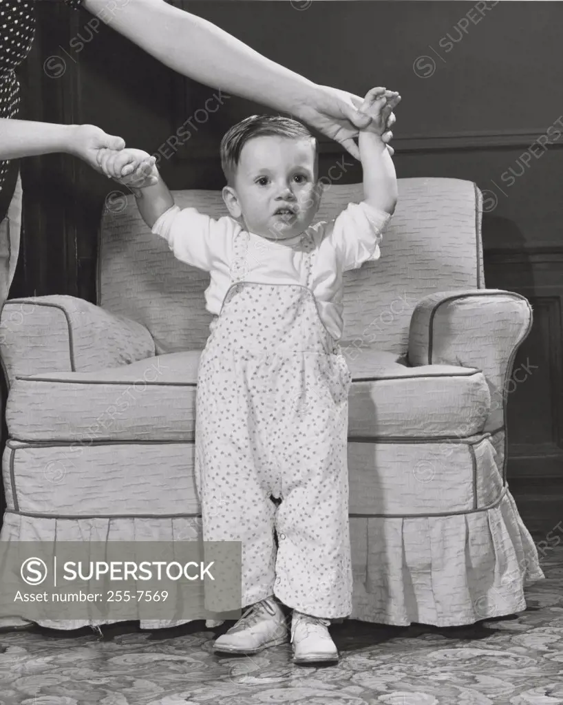 Baby girl standing in front of an armchair