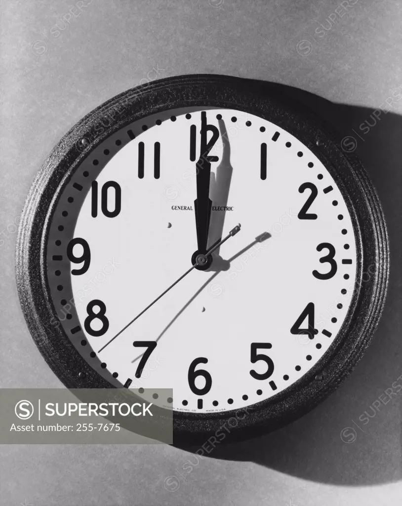 Vintage Photograph. Wall-mounted General Electric wall clock with harsh shadows, time set to 12:00