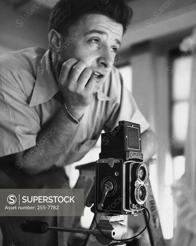 Photographer near a camera with his hand on his chin