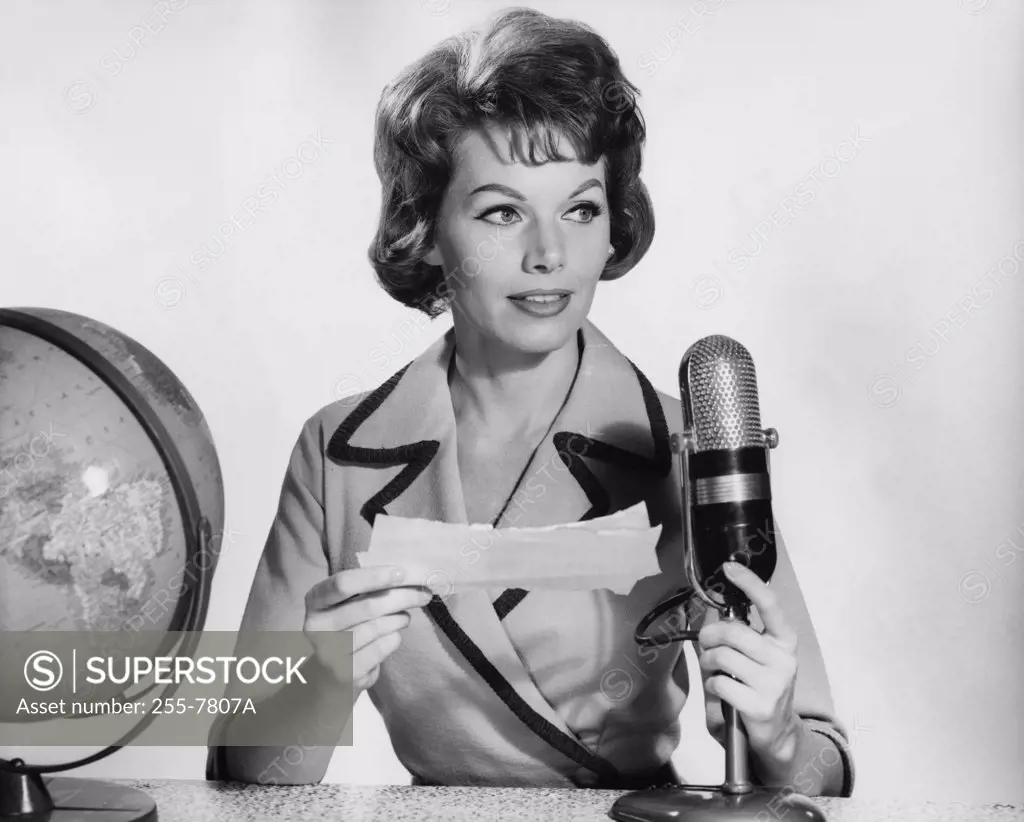 Mid adult woman reading a report on a microphone