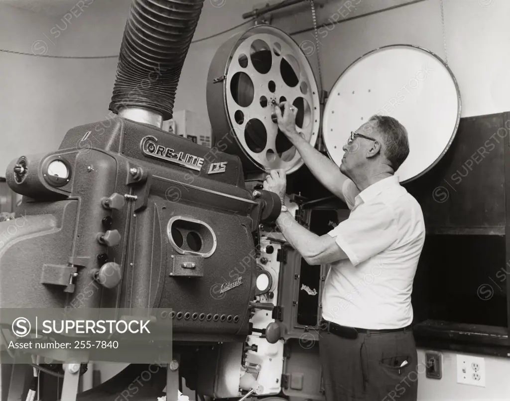 Side profile of a mature man operating a film projector