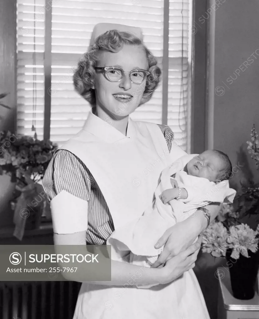 Portrait of a female nurse carrying a newborn baby boy