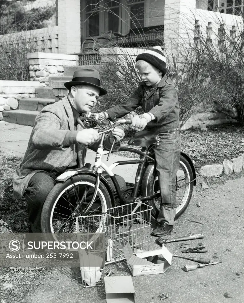 Close-up of a father repairing a bicycle with his son
