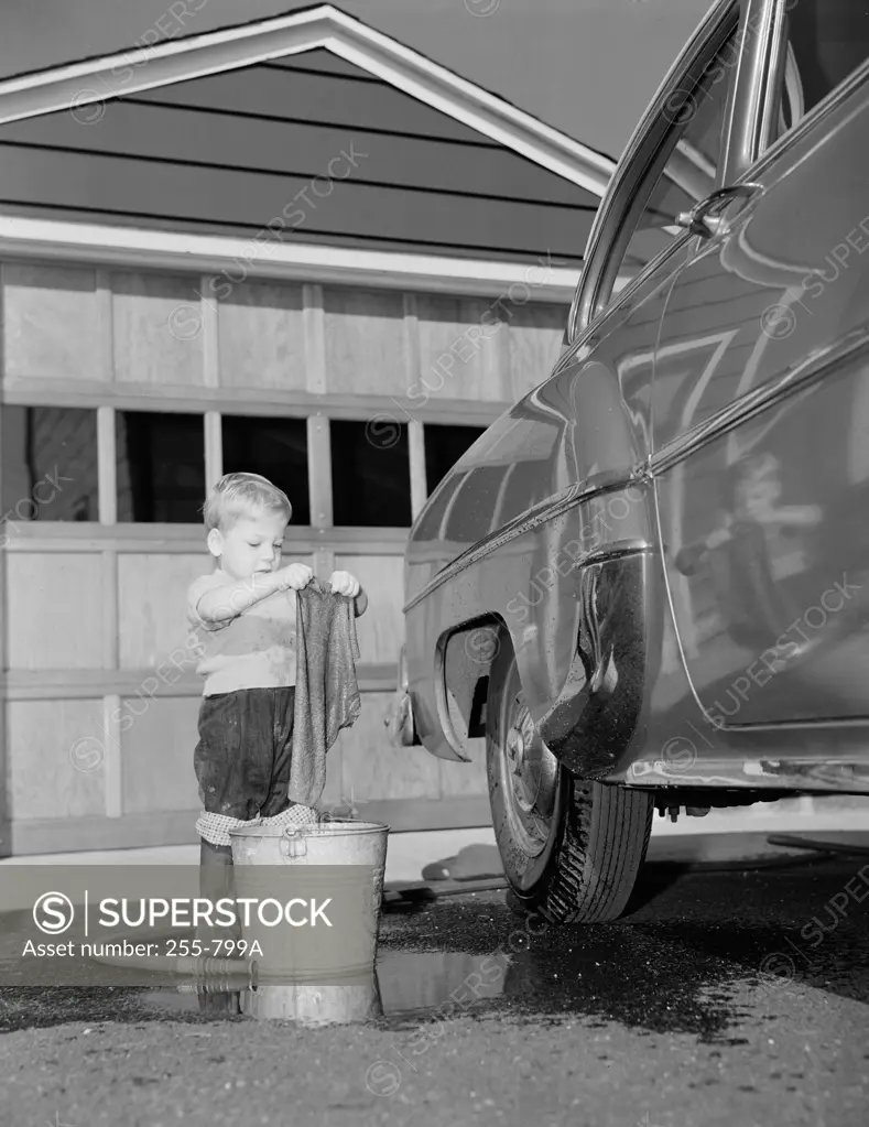 Boy washing car in front of house
