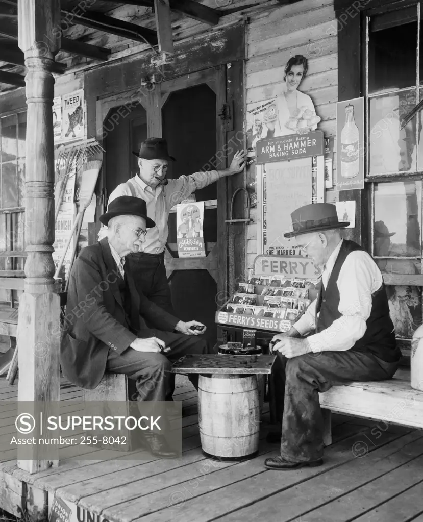 Side profile of two mature men playing checkers and another mature man standing beside them, Maine, USA