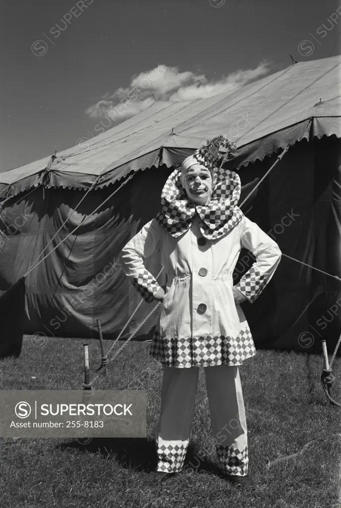 Vintage Photograph. Clown standing with arms akimbo in front of a circus tent