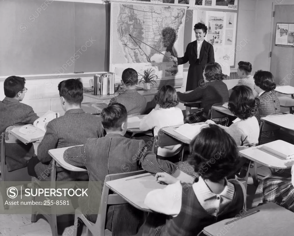 Female teacher pointing to a map in a classroom