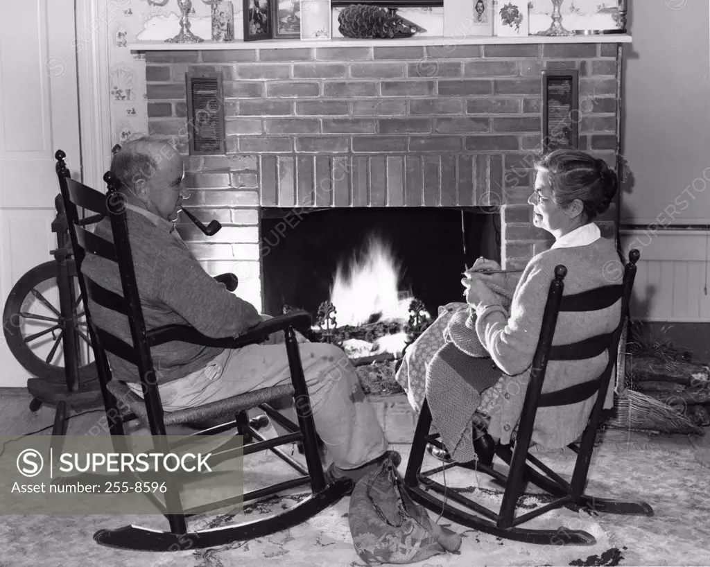 Senior couple sitting on rocking chairs in front of fireplace