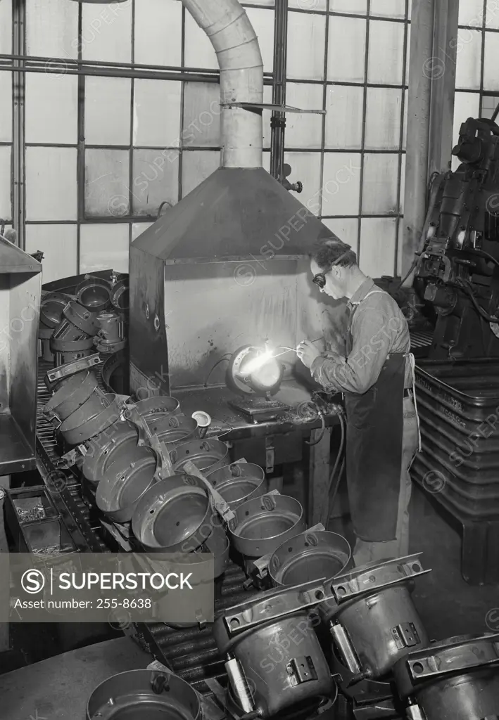 Vintage Photograph. Workman using sil-fos to hard solder copper tubes to the steel refrigerator compressor shell
