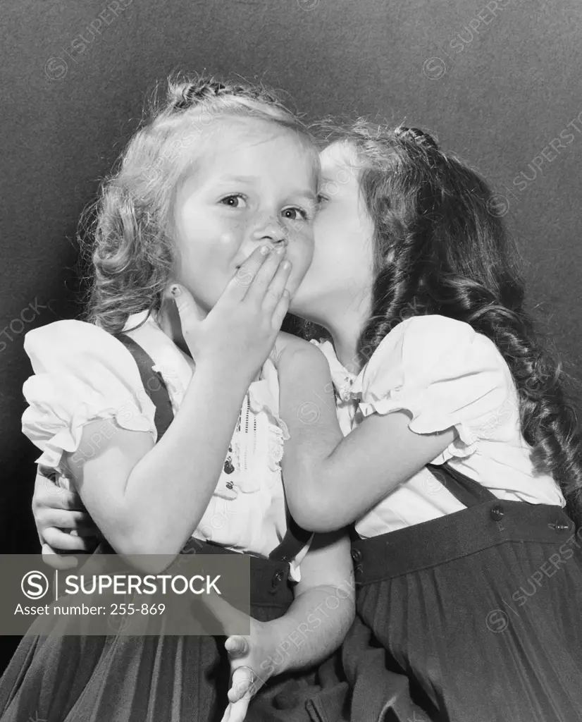 Girl whispering in her sister's ear