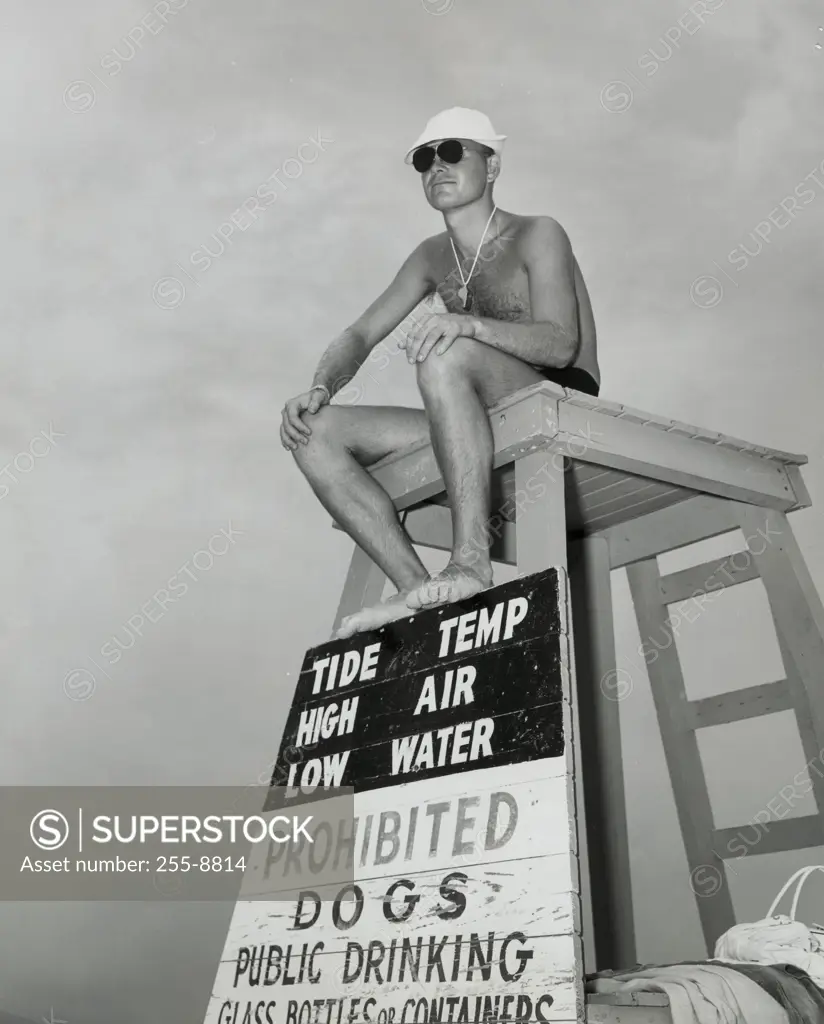 Low angle view of a young man sitting on a lifeguard's chair
