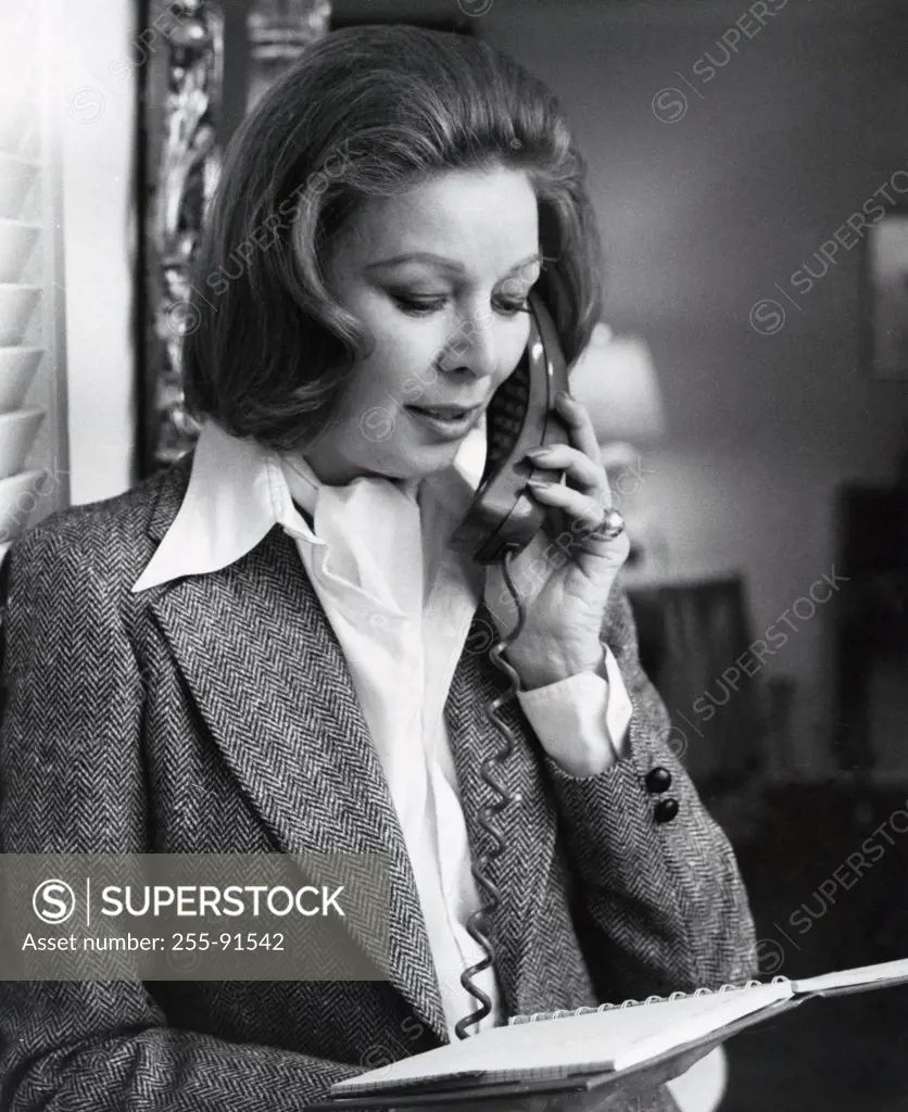 Woman reading document and talking on phone