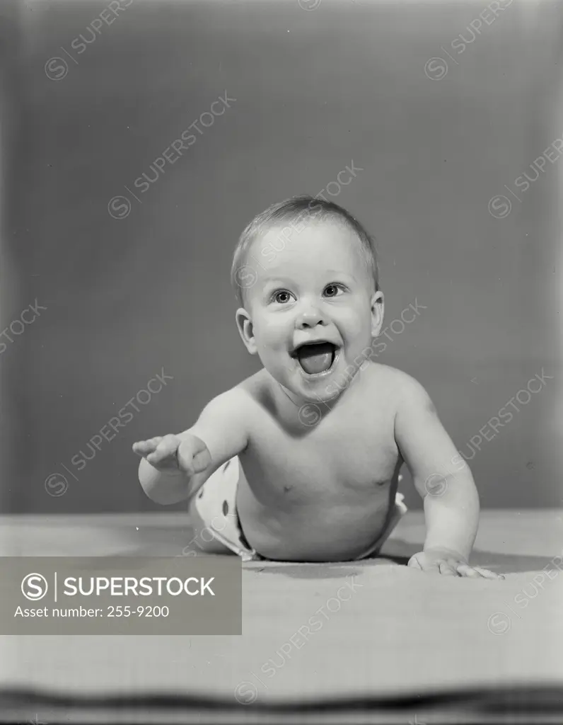 Vintage Photograph. Shirtless baby laying on stomach smiling