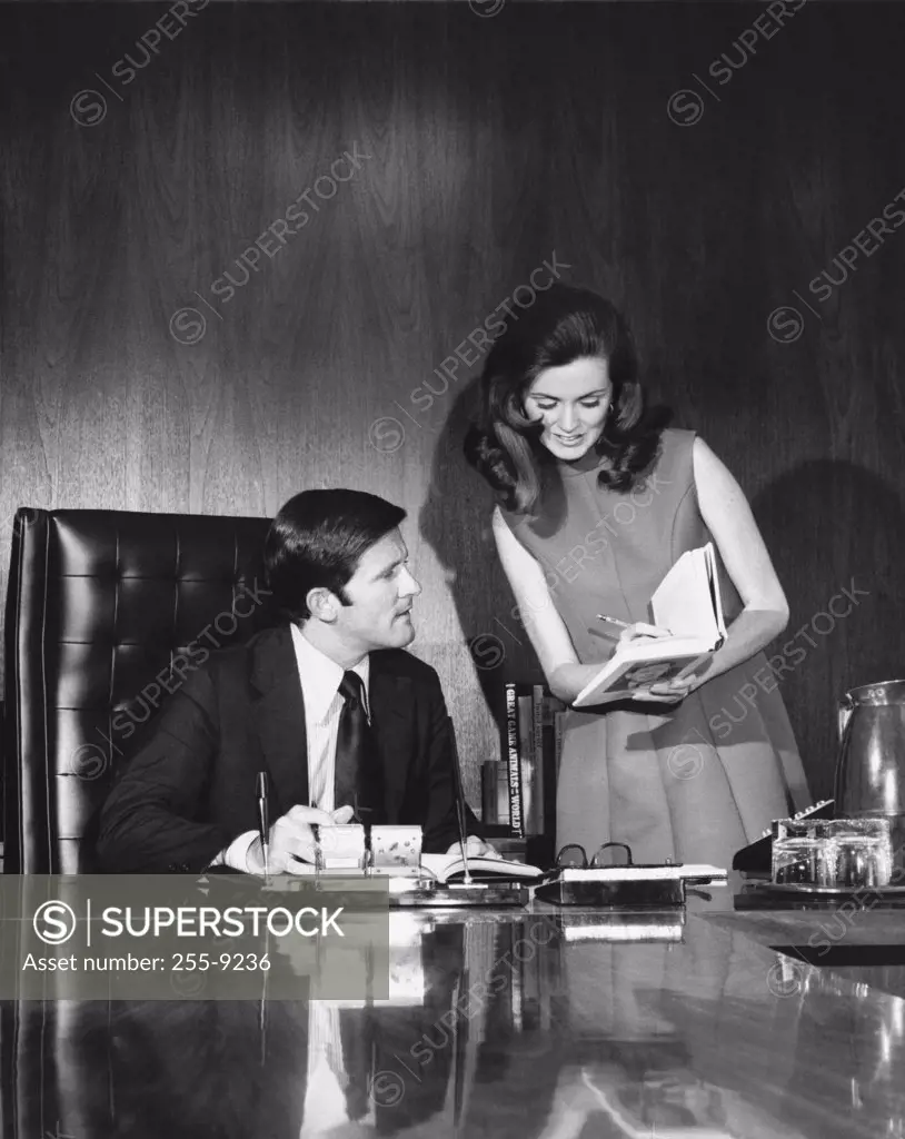 Businessman and his secretary looking at a book