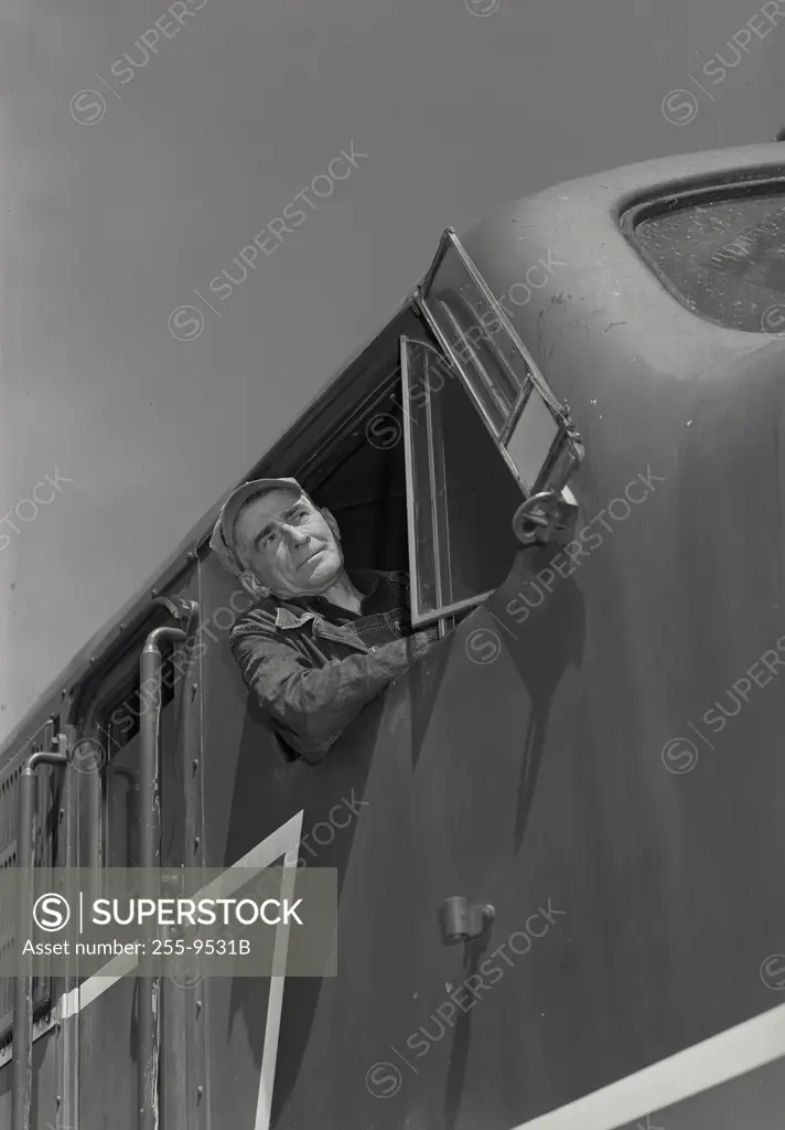 Vintage Photograph. Closeup of Railroad engineer looking ahead out of the window of a locomotive