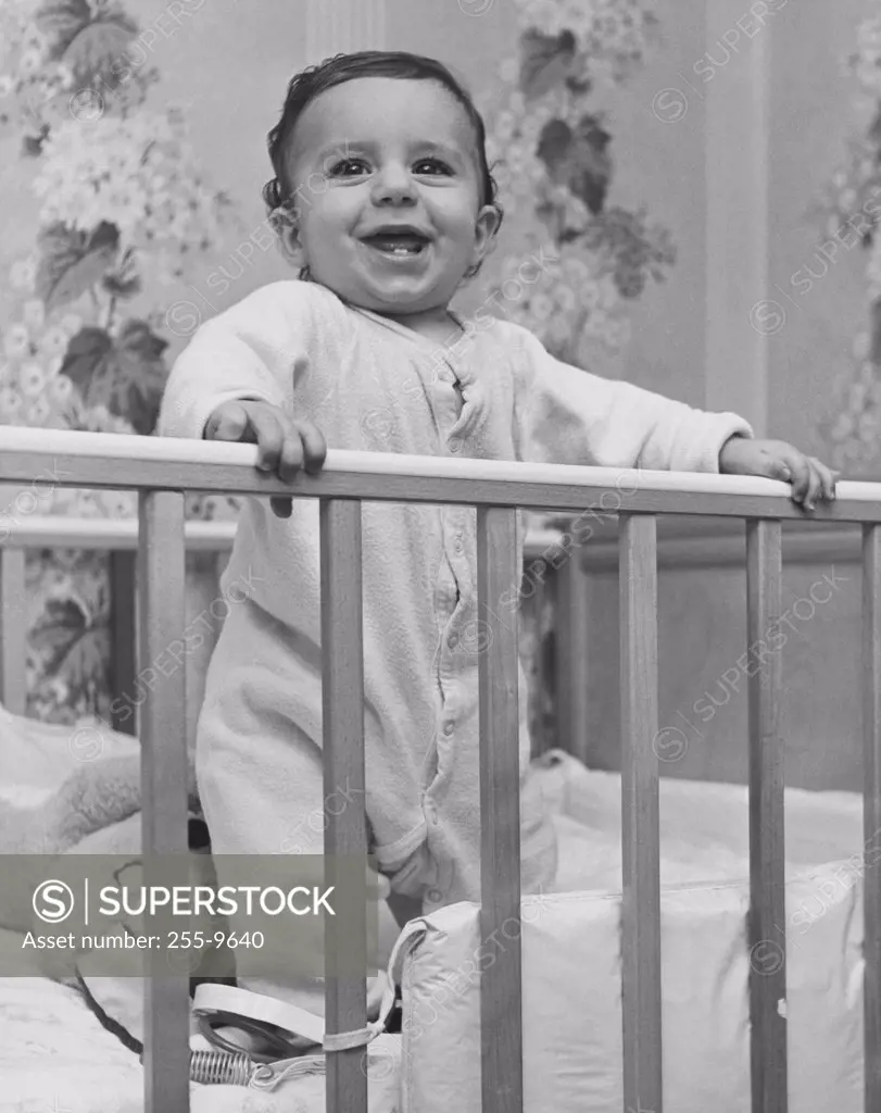 Baby smiling and standing in a crib