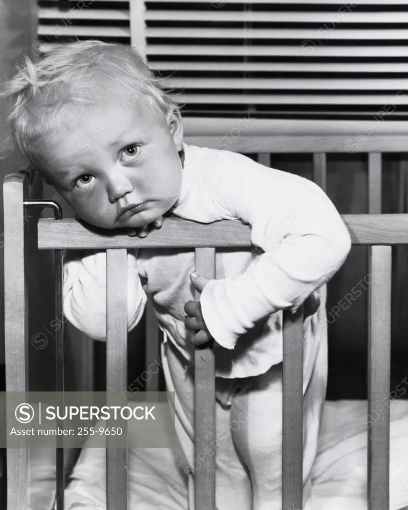 Close-up of a baby boy leaning over a crib